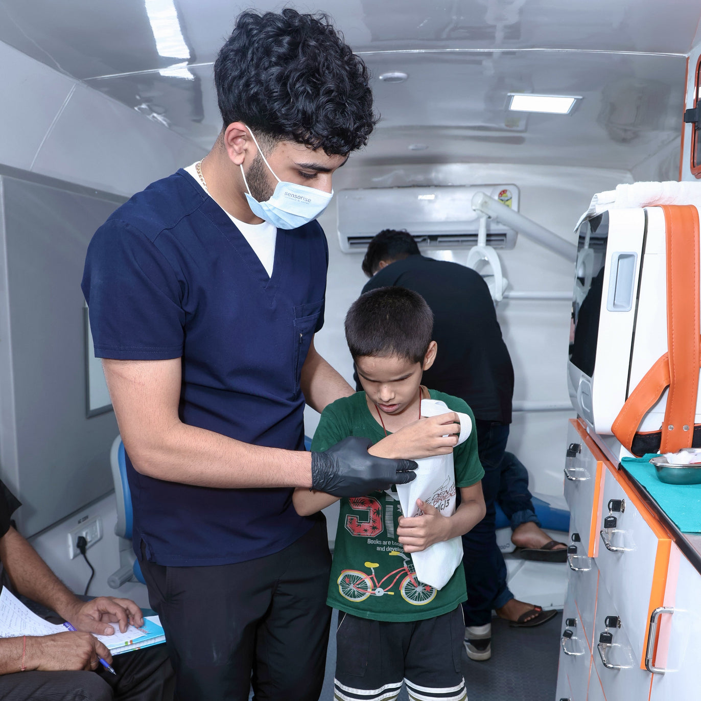 Person in a medical setting assisting a child with a medical device.